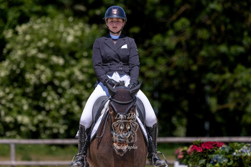 Portrait de face d'une cavalière à cheval en tenue d'équitation.